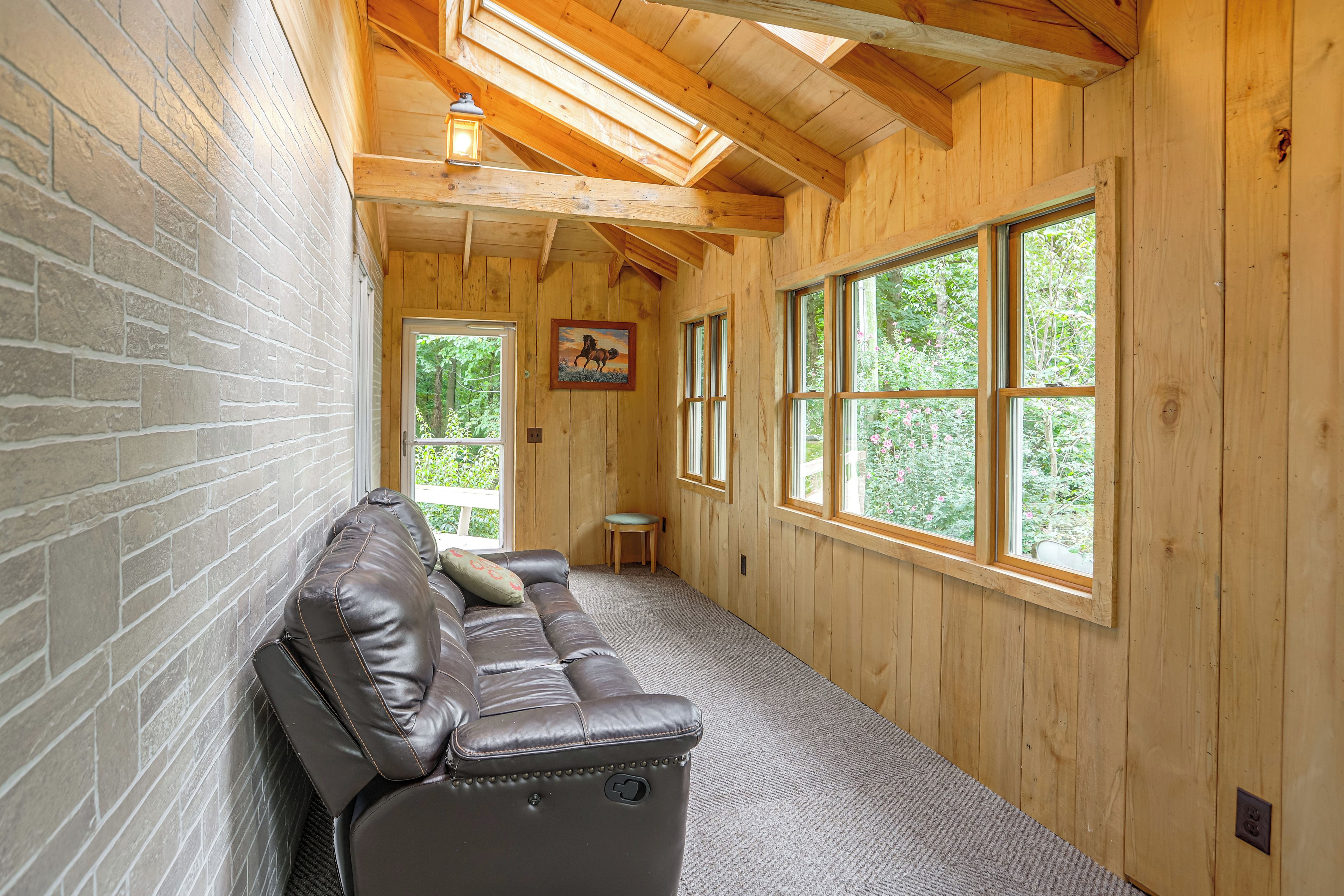A wooden interior with a leather bench, large windows, and a painting on the wall.