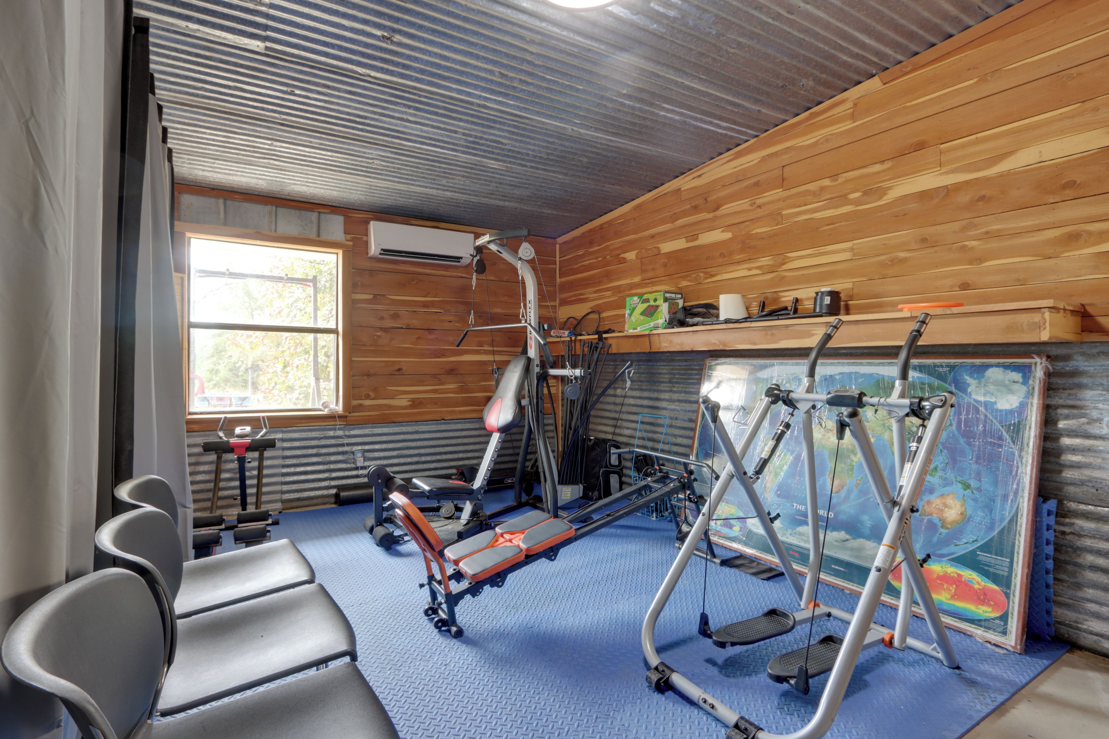 A gym with exercise equipment, a window, and a map on the wall.