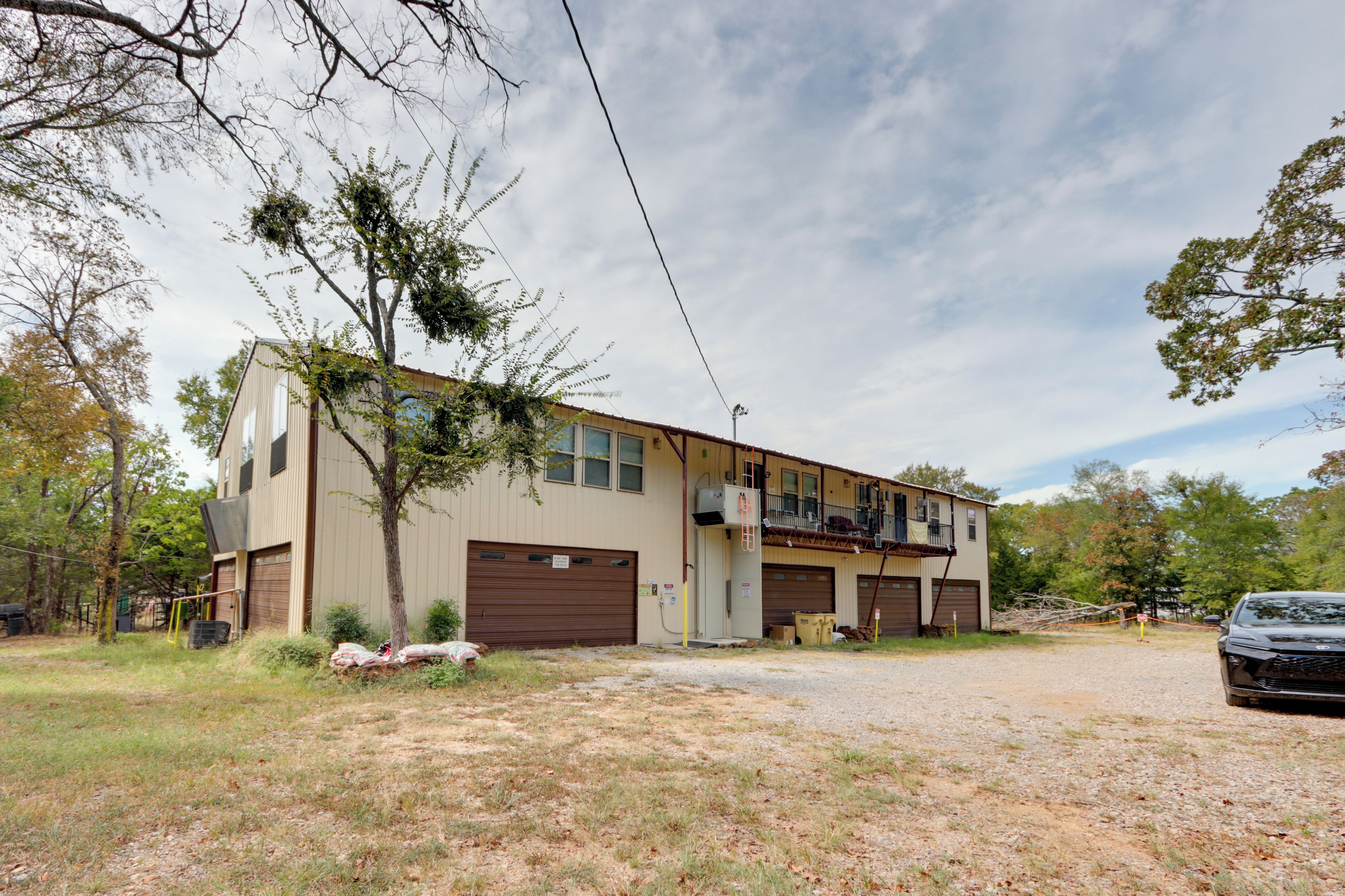 A two-story building with a garage, a balcony, and a gravel driveway.