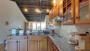 A kitchen with wooden cabinets, a granite countertop, a built-in oven, and a coffee maker.