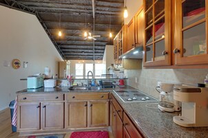 Una cocina con armarios de madera, encimera de granito, horno empotrado y cafetera.