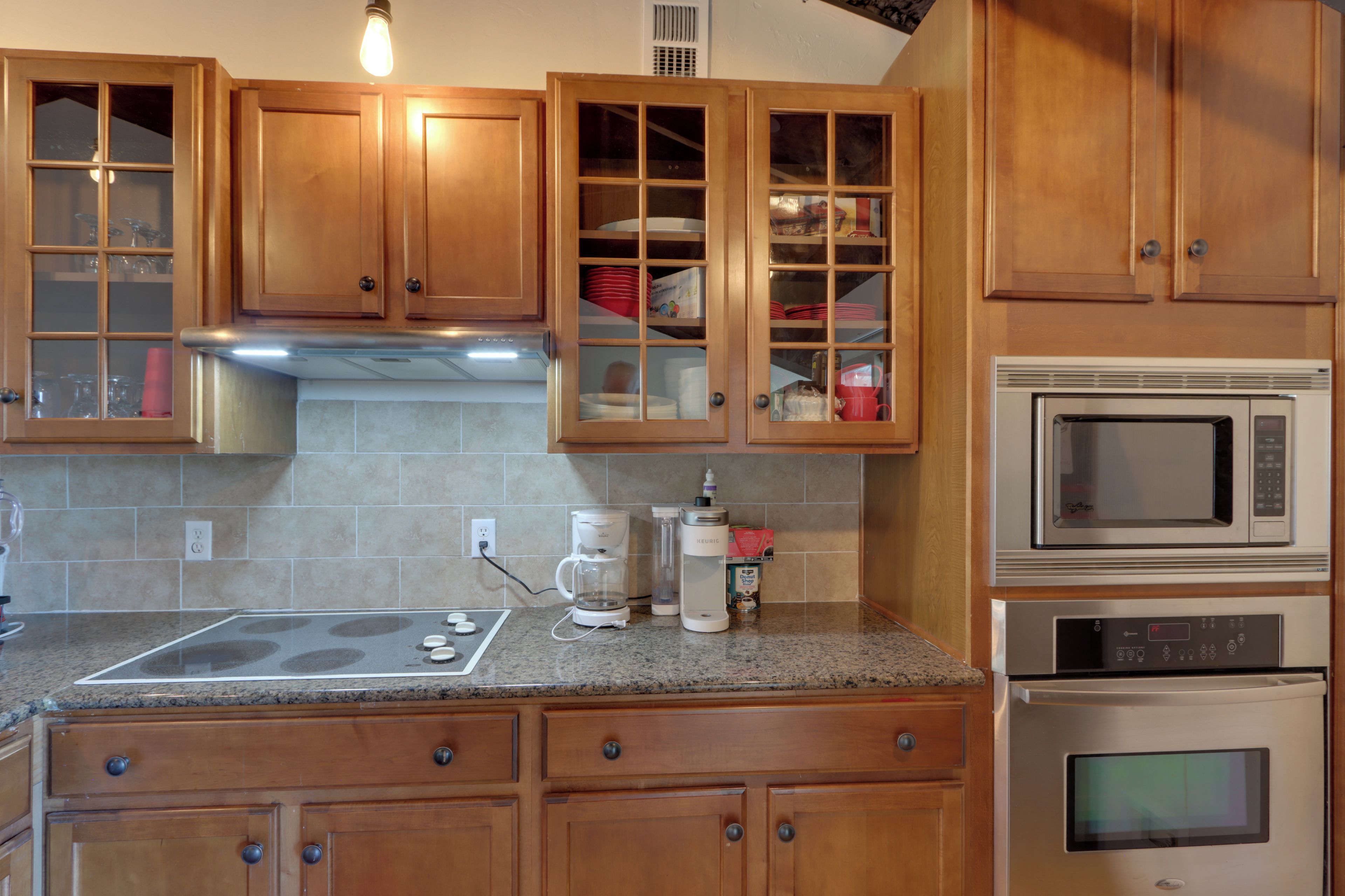 A kitchen with wooden cabinets, a built-in oven, a microwave, and a coffee maker.