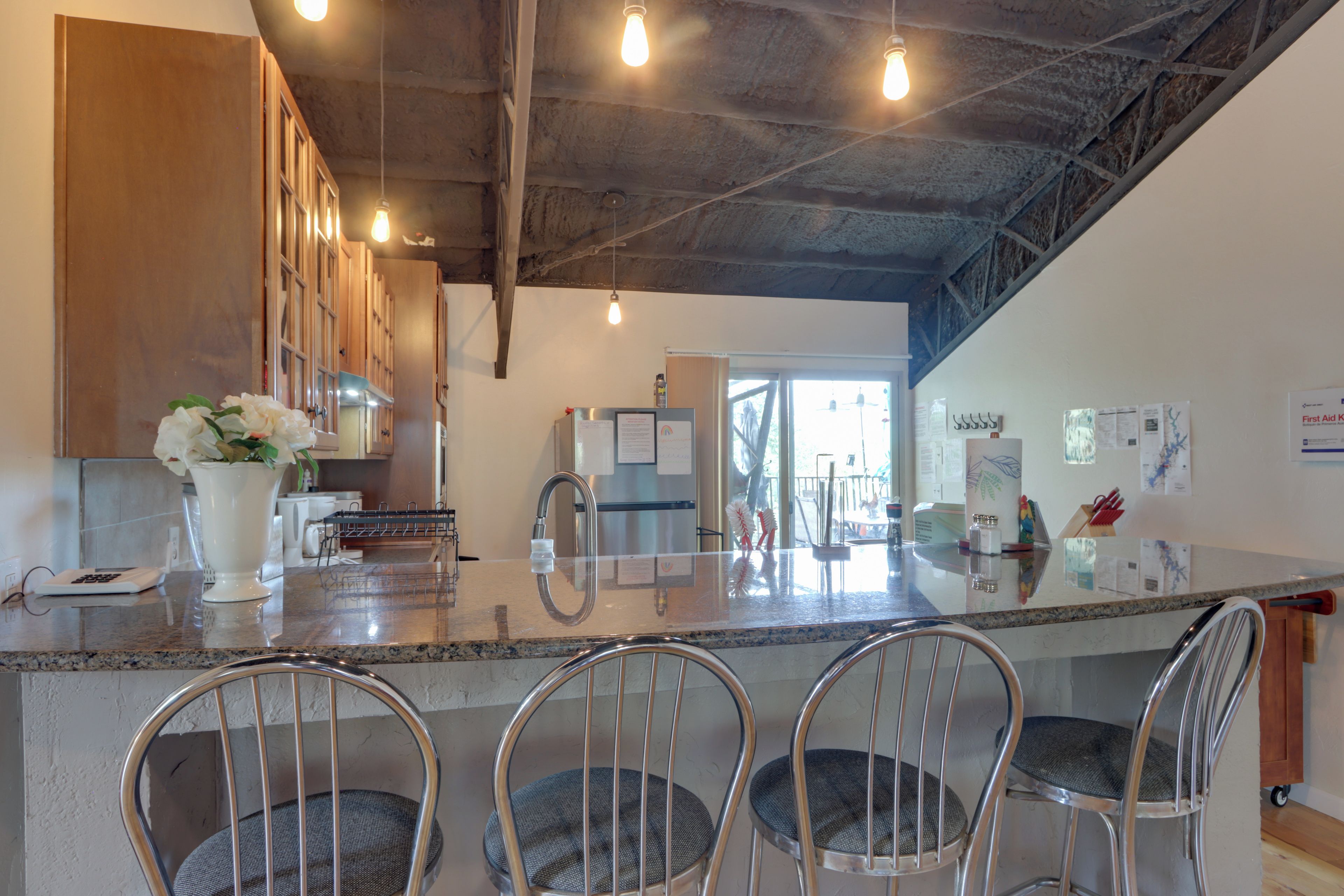 A modern kitchen with a central island, bar stools, and a view into the dining area.