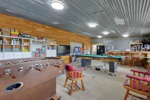 A billiards room with a pool table, chairs, and a foosball table.
