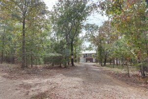 A forested area with a dirt path leading to a building with a garage.