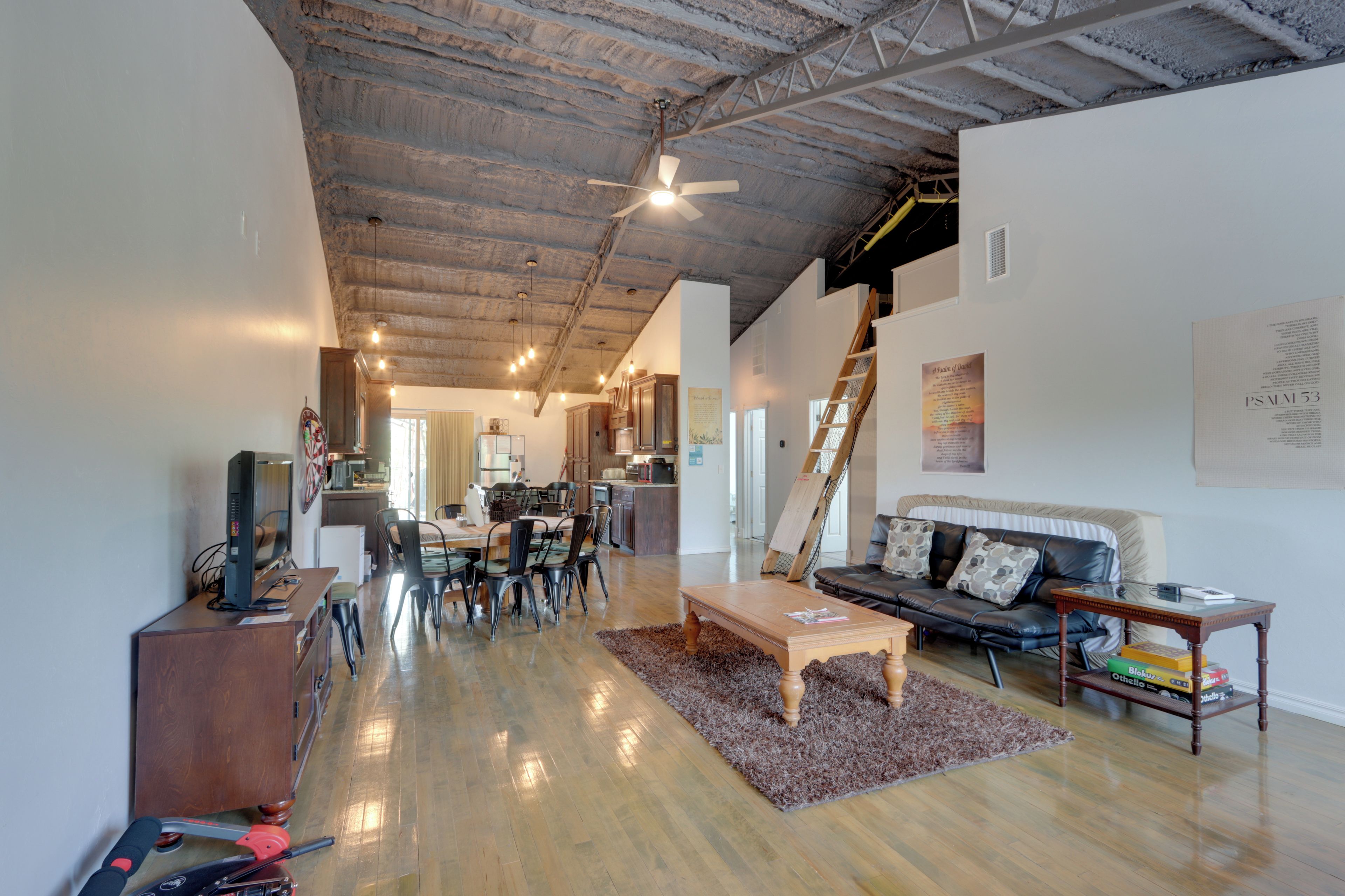 A spacious living area with a high ceiling, a dining table, and a sofa.