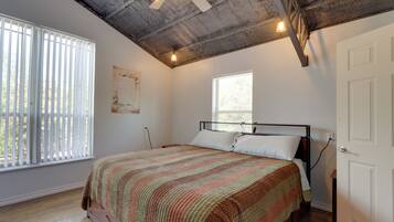 A bedroom with a bed, a ceiling fan, a window, and a door.