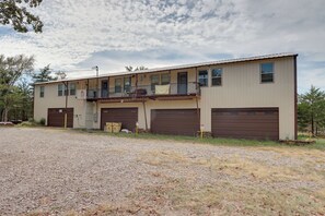 A two-story building with a flat roof, a balcony on the second floor, and two garage doors. - 1/2 Mi to Lake Tenkiller Condo w/ Shared Game Room (Cookson)