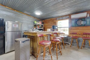 A kitchen with a refrigerator, a coffee machine, and a dartboard on the wall. - 1/2 Mi to Lake Tenkiller Condo w/ Shared Game Room (Cookson)