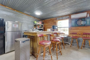 Una cocina con refrigerador, cafetera y un dardo en la pared.