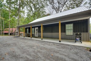 A building with a covered porch, a door, and a window. - Home Near Kentucky Lake & Paris Landing! (Buchanan)