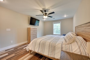 A bedroom with a bed, a ceiling fan, a TV mounted on the wall, and a window. - Home Near Kentucky Lake & Paris Landing! (Buchanan)