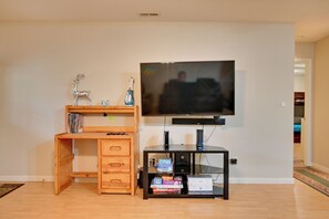 Ein Wohnzimmer mit einer Holzunterhaltungsecke, einem flachbildfernseher an der Wand und einem kleinen Schrank mit elektronischen Geräten.