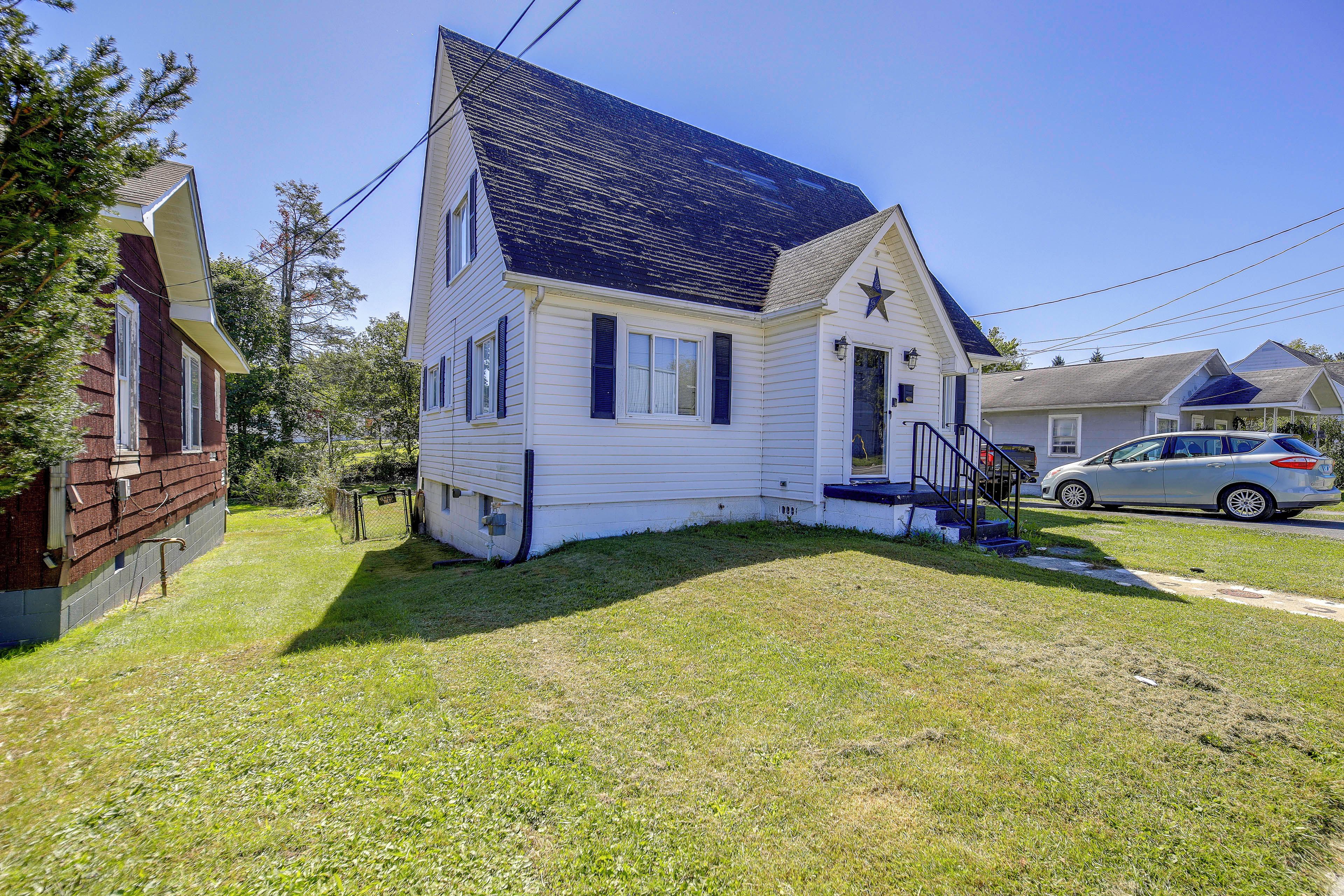 A single-story house with a dark roof, a front porch, and a small yard.