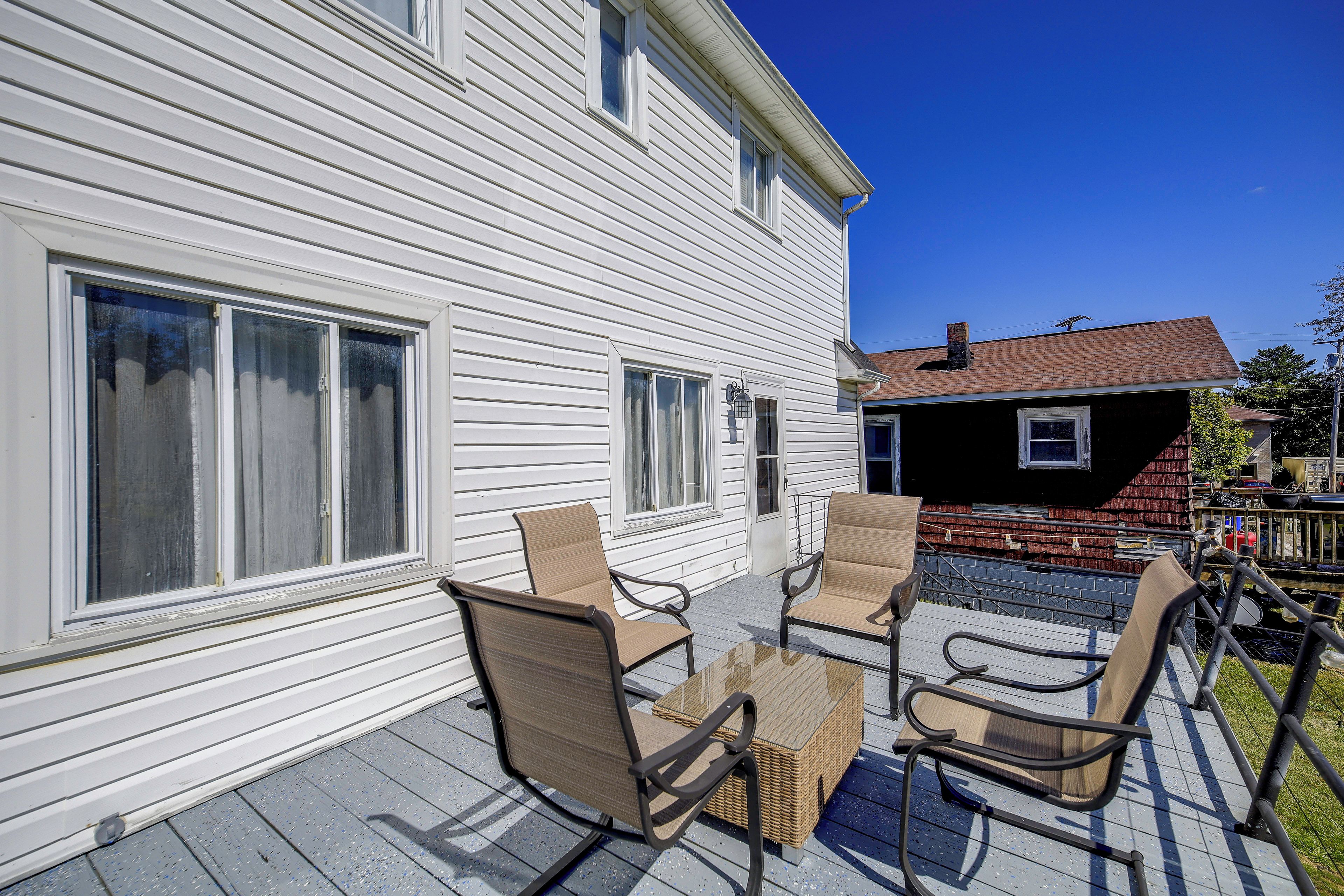 A patio with outdoor furniture and a view of a white house with multiple windows.