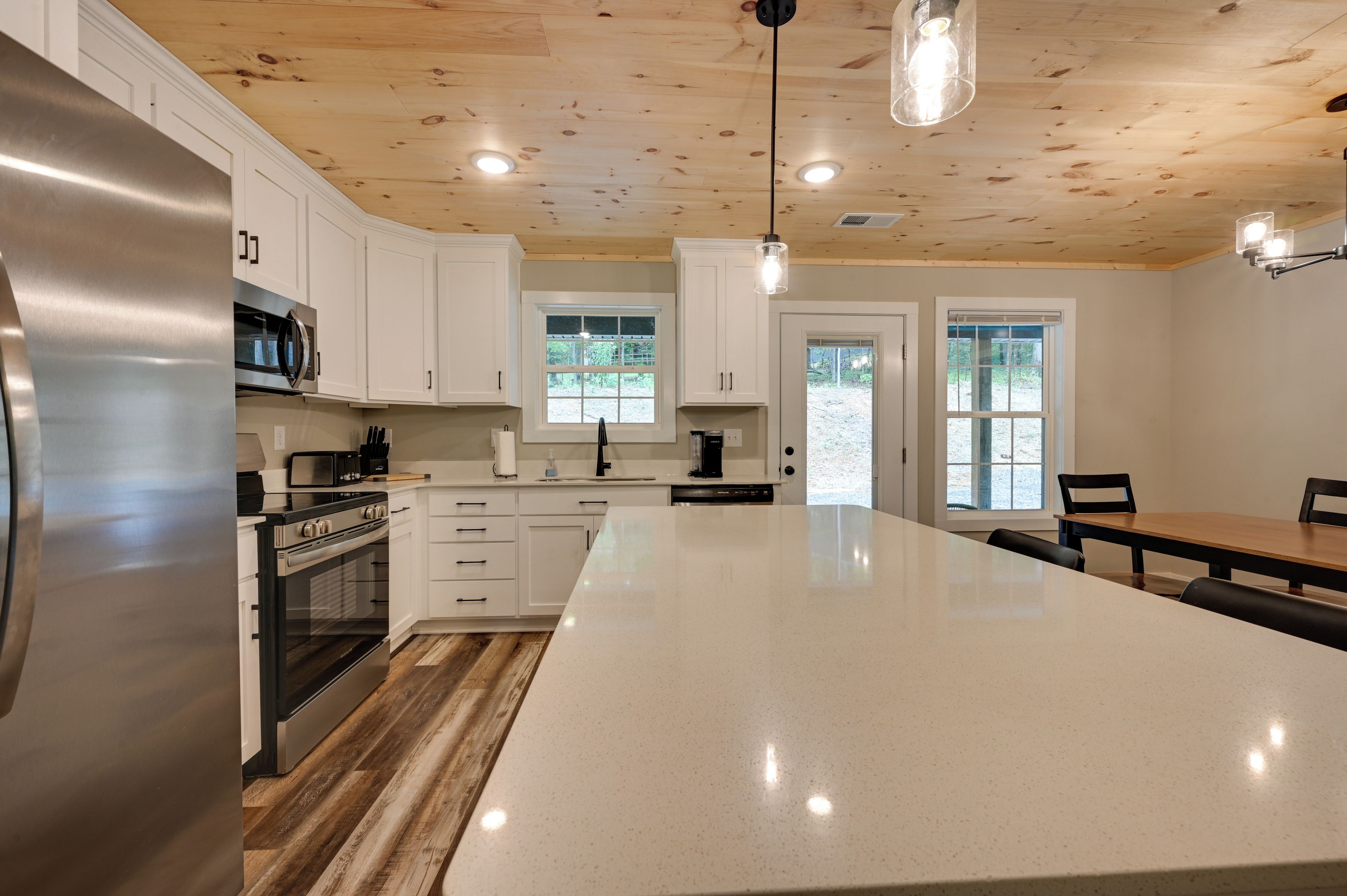 A modern kitchen with white cabinets, stainless steel appliances, and a large island.