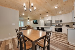 A modern kitchen with white cabinets, stainless steel appliances, and a wooden dining table with chairs. - Walk to Lake & Paris Landing State Park! Quiet Gem (Buchanan)