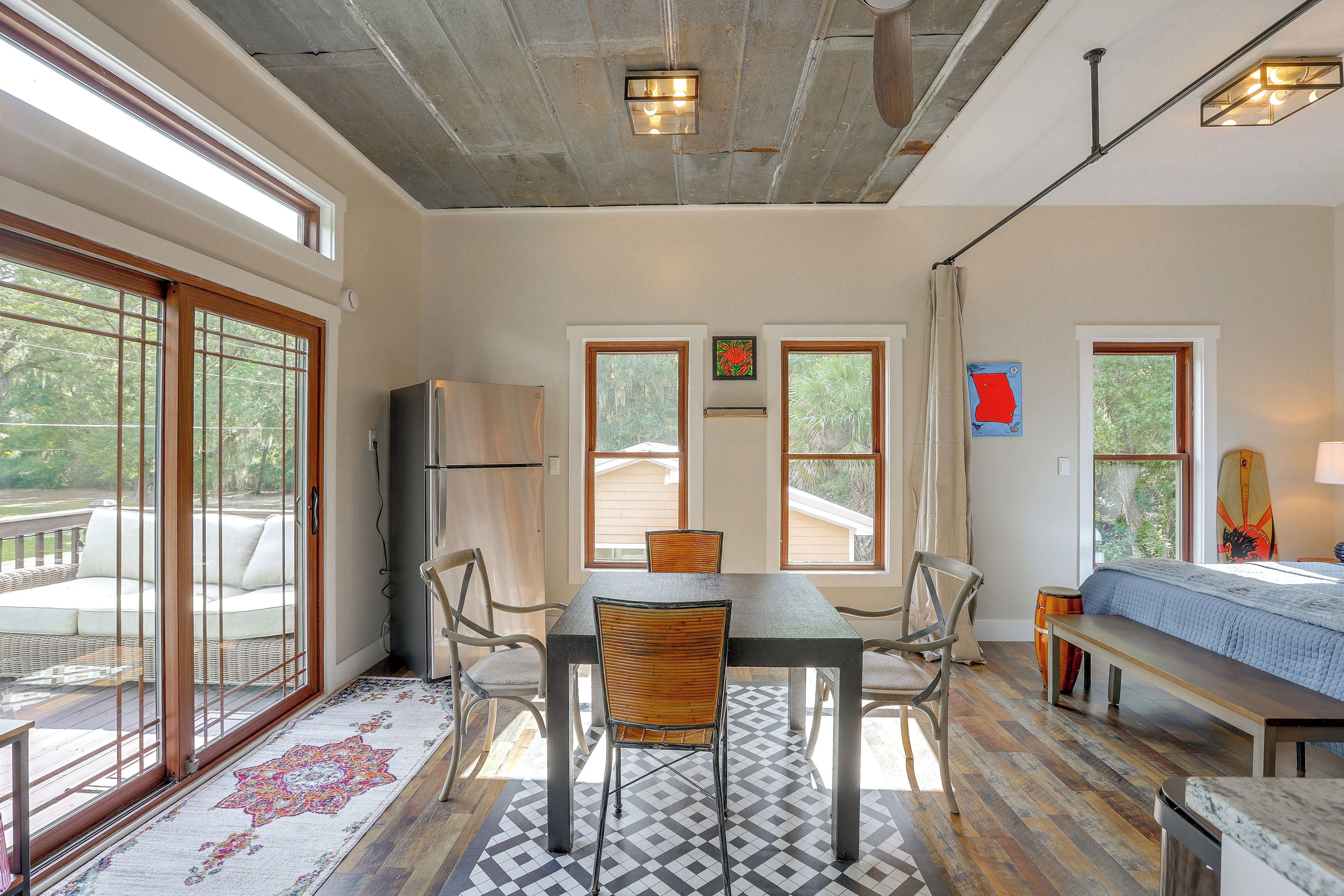 A spacious room with a dining table, chairs, a sofa, and a kitchen area.