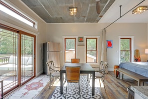 A spacious room with a dining table, chairs, a sofa, and a kitchen area.