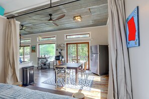 A spacious kitchen with a dining area, large windows, and a ceiling fan.