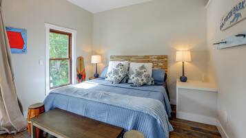 A bedroom with a bed, bedside lamps, a wooden headboard, a window, and a map on the wall.