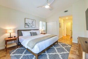 A bedroom with a bed, bedside lamps, a ceiling fan, a window with blinds, a door, and a hallway. - 3 Mi to Downtown! Sauna & Pool in Palm Springs (Palm Springs)