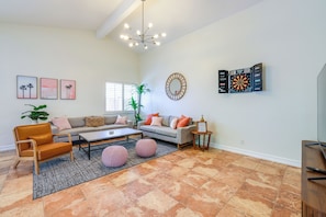 A living room with a sofa set, coffee table, and a dartboard. - 3 Mi to Downtown! Sauna & Pool in Palm Springs (Palm Springs)