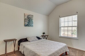 A bedroom with a bed, a nightstand, a window with blinds, and a wall-mounted artwork. - Home Theater & Game Room! 7BR San Antonio Retreat (San Antonio)