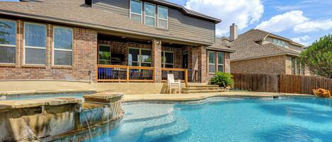 A residential property with a swimming pool, a covered patio, and a brick exterior.