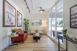 A spacious living room with a brown leather sofa, a coffee table, and a large window offering a view of the city. - 1 Block to Sand! Ocean-view Retreat w/ Pool Access (Fort Lauderdale)