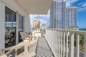A balcony with outdoor furniture, a view of high-rise buildings, and a clear sky. - 1 Block to Sand! Ocean-view Retreat w/ Pool Access (Fort Lauderdale)