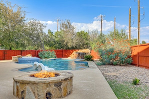 A backyard with a swimming pool, a stone fire pit, and a wooden fence. - Private Pool & Hot Tub: San Antonio Home (San Antonio)