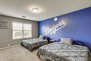 A bedroom with two beds, a window with blinds, a ceiling light, and a wall mural with the word 'Dodgers'. - Private Pool & Hot Tub: San Antonio Home (San Antonio)