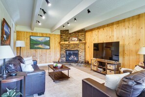 A cozy living room with a fireplace, leather sofas, a flat-screen TV, and a painting on the wall. - Breckenridge Ski Condo: Easy Bus to Slopes (Breckenridge)