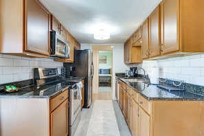 A kitchen with wooden cabinets, a microwave, a refrigerator, and a granite countertop. - Breckenridge Ski Condo: Easy Bus to Slopes (Breckenridge)