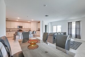 A modern kitchen with white cabinets, a microwave, and a dining area with a glass-top table and chairs. - Port St. Lucie Home on Florida's Treasure Coast (Port Saint Lucie)
