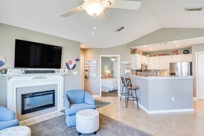 Ein modernes Wohnzimmer mit Kamin, Flachbildfernseher und Deckenventilator.