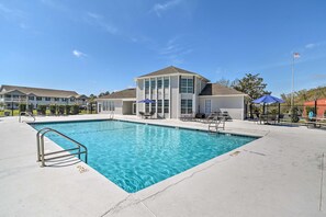 A swimming pool with a metal ladder, surrounded by lounge chairs and a building with large windows. - 5 Mi to Beach! Gulf Shores Condo w/ Pool & Hot Tub (Gulf Shores)