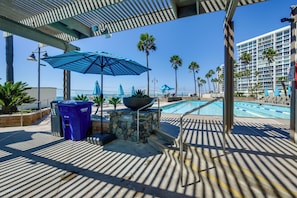 A poolside area with umbrellas, a trash bin, and a stone wall. - Beach + Poolside Days! Extended Coronado Escape (Coronado)