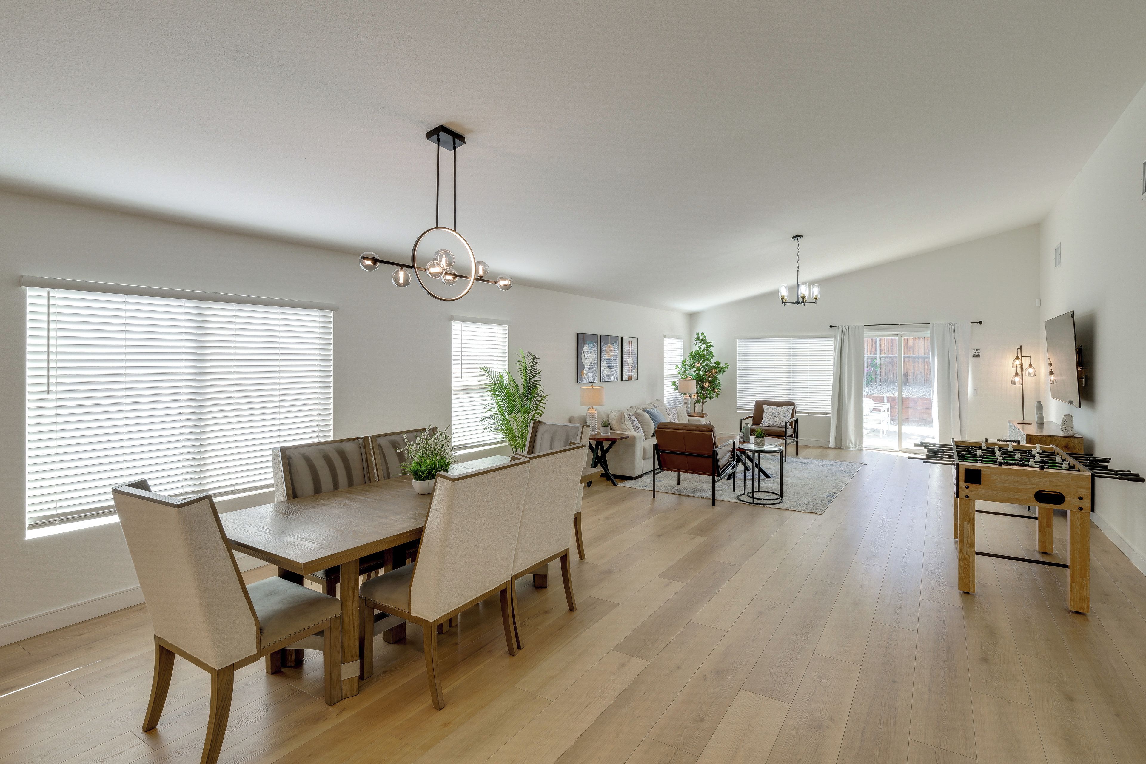 A spacious living area with a dining table, sofas, and a foosball table.