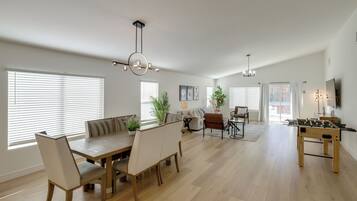 A spacious living area with a dining table, sofas, and a foosball table.