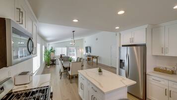A modern kitchen with a central island, stainless steel appliances, and a dining area with a table and chairs.