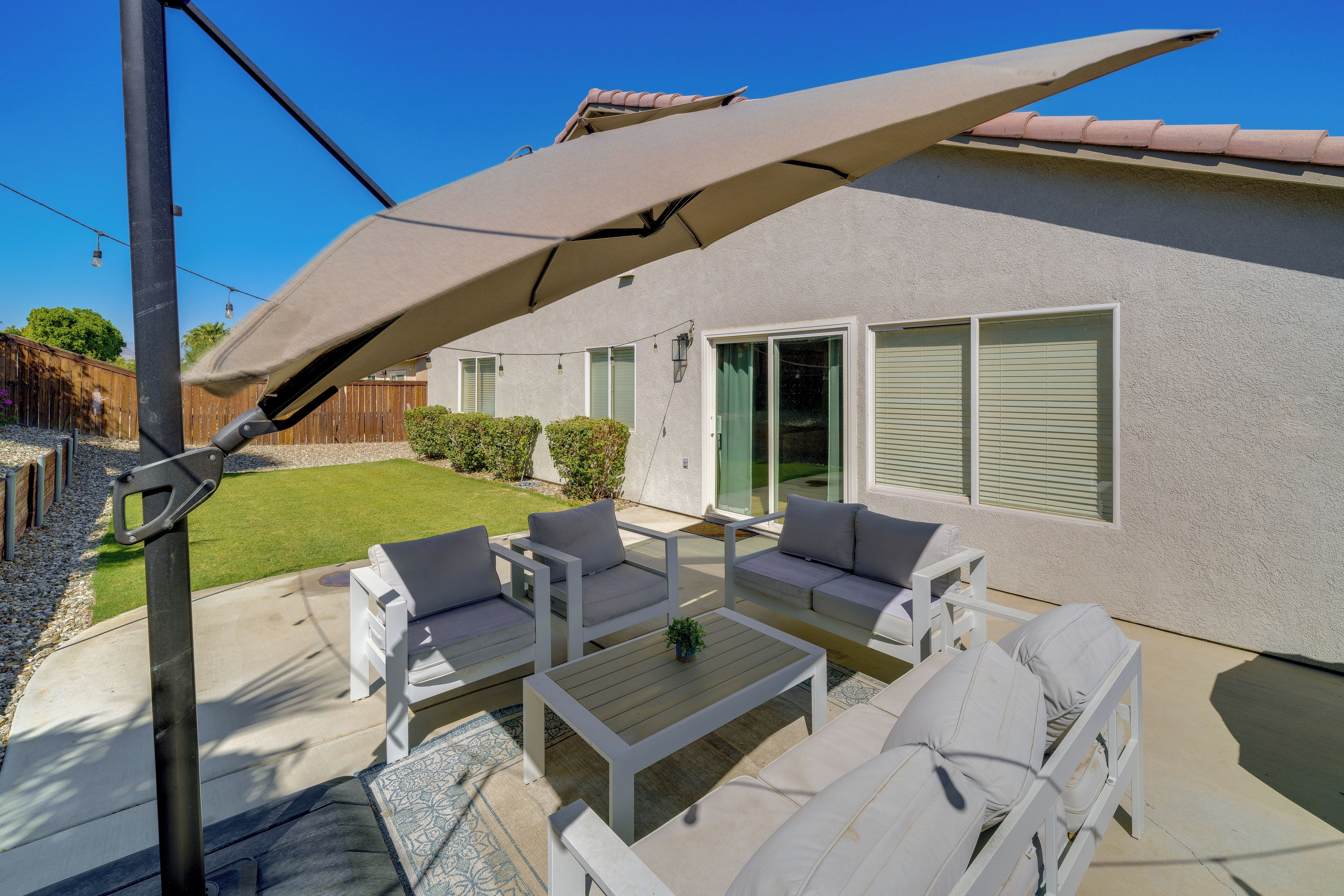 A patio with outdoor furniture, a pergola, and a house with a light-colored exterior.