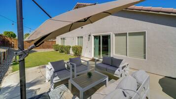 A patio with outdoor furniture, a pergola, and a house with a light-colored exterior.