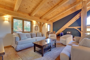 Une pièce chaleureuse avec un plafond en bois, un canapé, un fauteuil et une table.