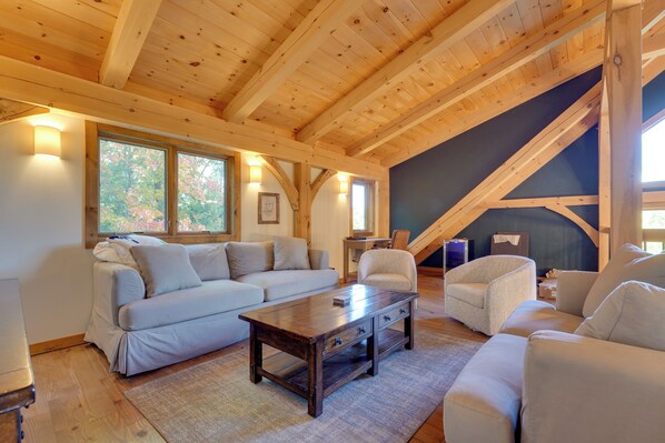A cozy room with a wooden ceiling, a sofa, a chair, and a table.