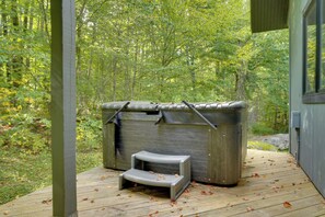 A hot tub on a wooden deck with a view of a forest.