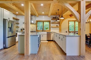 A modern kitchen with wooden beams, a stainless steel refrigerator, and a large island.
