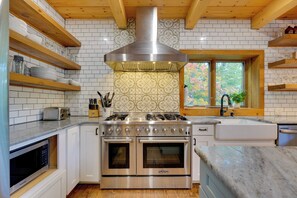 A modern kitchen with white cabinetry, stainless steel appliances, and a patterned backsplash.