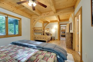 A bedroom with a bunk bed, a ceiling fan, and a window.